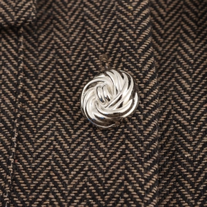 Veste en tweed à chevrons marron avec un bouton métallique argenté gaufré en spirale