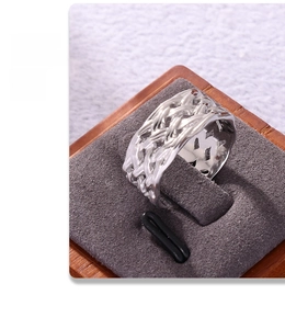 Macro shot of silver textured ring with woven design on a gray and wood display stand