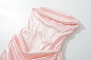 Détail du tissu satin rose de la robe montrant une texture brillante et des plis