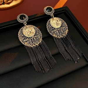 Detailed close-up of retro gold coin earrings with black tassels and French engraving