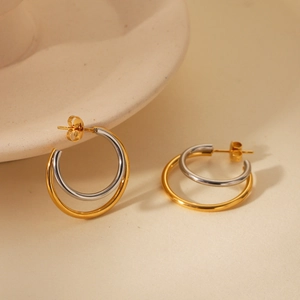 Close-up of double-layered gold and silver stainless steel earrings on ceramic