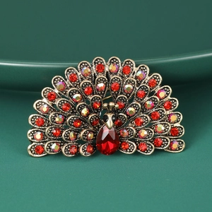 Detail shot of vintage gold peacock brooch with sparkling red rhinestones and teardrop stone