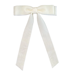 Close-up of off-white velvet bow hair clip with long ribbons and soft fabric texture