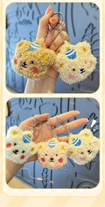 Detail of plush bear keychains in beige and pink with blue striped hat embroidery