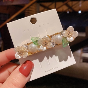 Detailed close-up of handmade shell flower hair clip with pearls and golden leaves