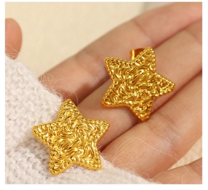 Detail of star-shaped gold stud earrings with a vintage hammered lava texture