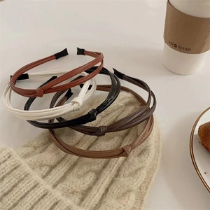 Detail of knotted PU leather headbands in earthy tones arranged on a cozy knit background