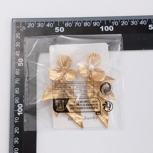 Detailed view of gold ginkgo leaf earrings with pearls measuring 85mm against a ruler