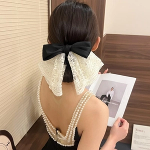 Elegant black satin hair clip with white floral lace bow on a model's back view