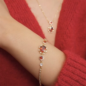 Detailed view of 18K gold plated jewelry set with red oval zircon on model wrist