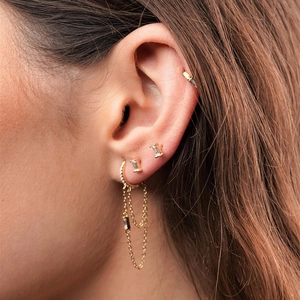 Detail view of gold chain tassel earrings and rectangular zircon studs on model