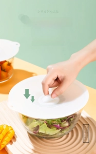 Detail of white silicone food cover creating vacuum seal on a glass salad bowl
