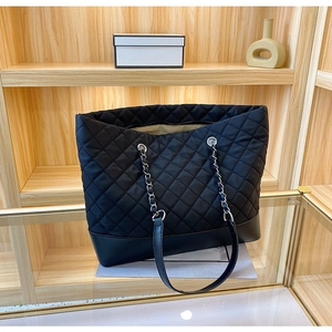 Borsa tote in nylon trapuntato con catena e base in pelle in un espositore di vendita
