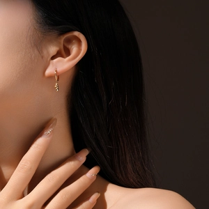 Close-up of a woman wearing gold S925 silver hoop earrings with spiral conch pendants