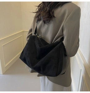 Detail of minimalist black suede pillow bag showing large capacity and zipper closure