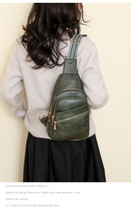 Deep green leather chest bag with geometric strap shown on a model wearing a beige sweater