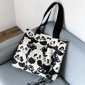 Detail of cute panda printed canvas tote bag placed on a grey sofa in home setting