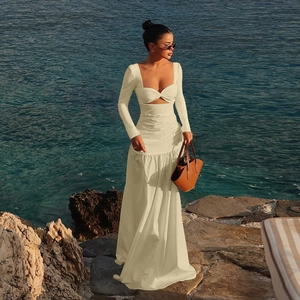 Detail of beige hollow-out long sleeve dress with cross neckline on a coastal rock