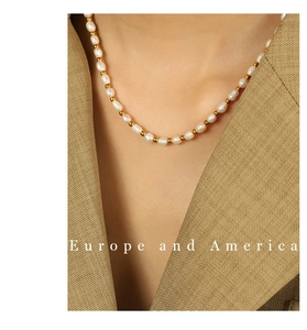Detail of baroque pearl necklace with gold beads worn with a tan blazer