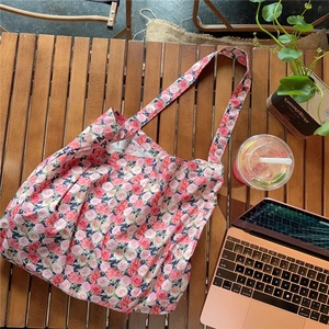 Close-up of floral tote bag with red roses on a vintage wooden table setting