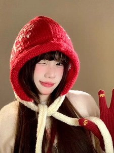 Detailed knit texture of red balaclava with white drawstrings and flower gloves