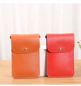 Détail des pochettes de téléphone en similicuir orange et rouge avec boutons pression