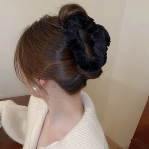 Detail of plush black faux fur hair claw clip styled on a low bun hair arrangement