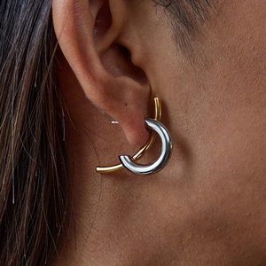 Model wearing gold and silver two-tone C-shaped hoop earrings in stainless steel
