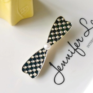 Detail of checkered bow hair clip with luxury faux pearls and sparkling rhinestones
