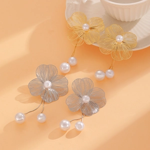Detail of elegant gold and silver hollow flower earrings with delicate pearl tassels