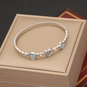 Detail of silver bangle featuring heart and round evil eye charms on a jewelry box