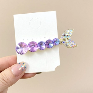 Sparkling mermaid tail hair clip with purple crystals on a golden metal base