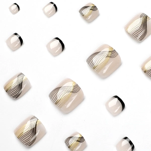 Faux ongles d'orteils nude avec lignes dorées et noires et bordures françaises modernes