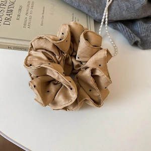 Close-up of khaki polka dot lace scrunchie with rich folds on a decorative background