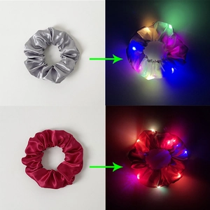 Detail of LED light-up satin hair scrunchies showing glow effect in dark and daylight view