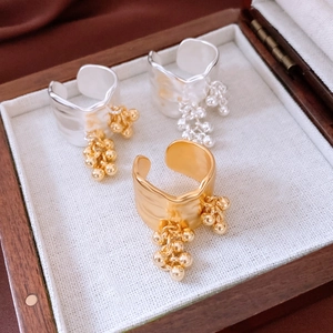Detailed view of 18K gold plated rippled rings with beaded fringe on wood jewelry display