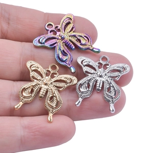 Three butterfly DIY pendants in gold, silver, and rainbow colors held for scale