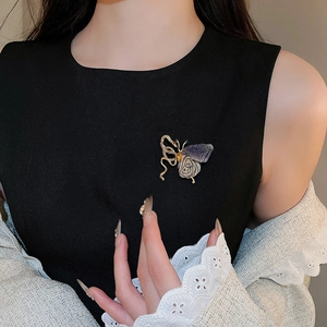 Detail of knit butterfly brooch with red rhinestones on a black dress and lace cardigan