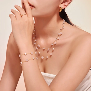 Set gioielli elegante con collane di perle rosa bracciali e orecchini d'oro indossati