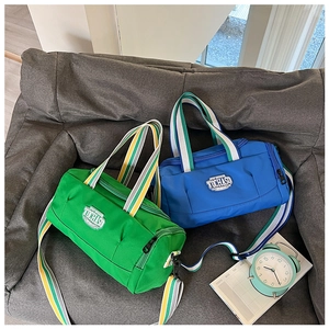 Detail of blue and green nylon barrel bags with striped straps and logo on a sofa