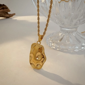 Detailed macro view of 18K gold stainless steel necklace with irregular hammered pendant