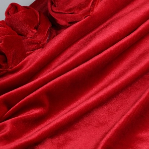 Detailed close-up of 3D rose fabric design on red velvet off-shoulder evening dress