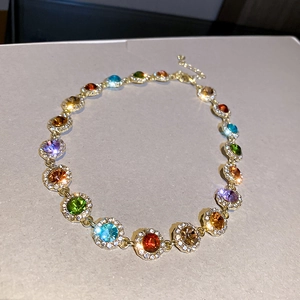 Detailed macro view of gold necklace featuring vibrant colorful gemstones with halos