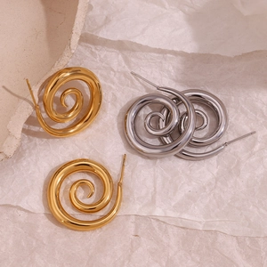 Artistic detail of gold and silver spiral metal stud earrings on a minimalist background