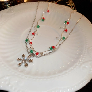 Close-up of a silver snowflake necklace with festive red, green and white beads