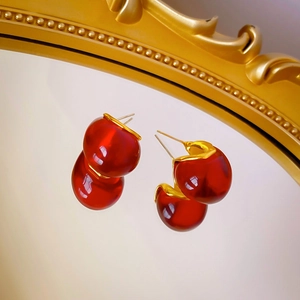 Vue macro de boucles d'oreilles en résine ambre dorée sur un miroir vintage