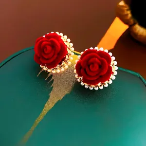 Elegant red velvet rose earrings with pearl trim on a luxury gold-plated setting