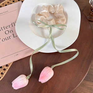 Detailed view of beige satin scrunchie with pink tulip tassels on a white decorative plate