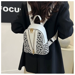 Close-up of leopard print detail and gold zippers on the white leather backpack