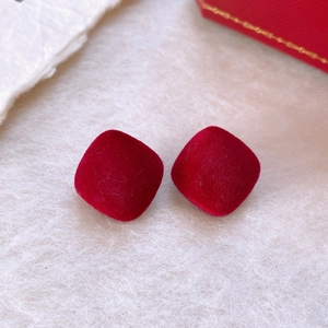 Vue macro de boucles d'oreilles carrées floquées rouges sur fond en peluche beige